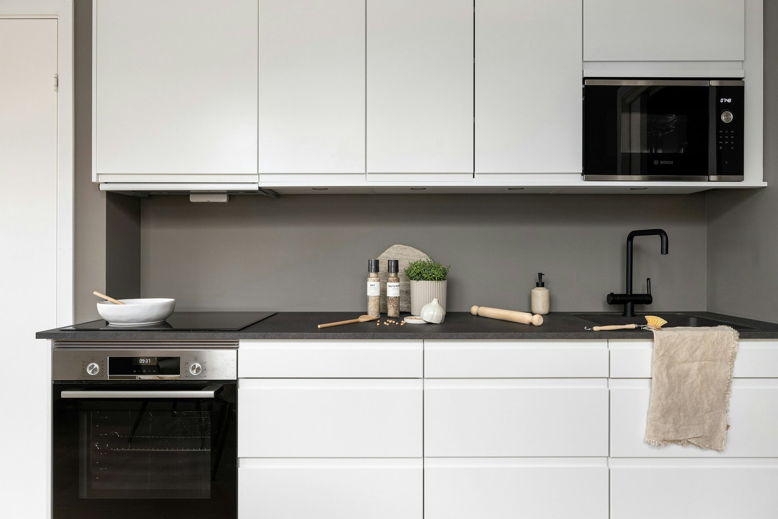 Hand sprüht Reinigungsmittel in den Innenraum einer geöffneten Mikrowelle