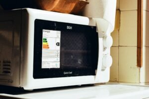 Kleine Schale mit weißem Pulver in einer geöffneten Mikrowelle